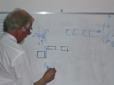 Man in white shirt drawing diagrams on a whiteboard, illustrating team collaboration.